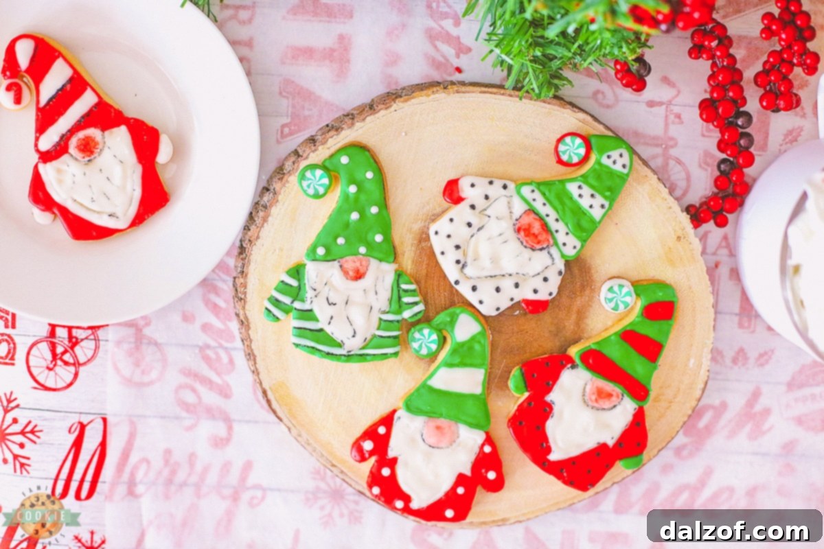 a close-up of a perfectly iced gnome cookie with a red hat, white beard, and green shirt, sitting on a white background.