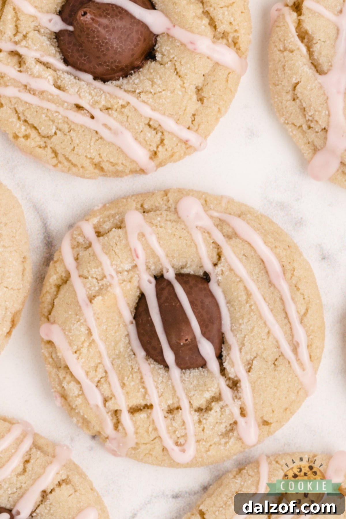 Almond Kiss Cookies made with almond extract and Hershey kisses with almonds! Drizzled with a simple raspberry glaze, these make a fantastic alternative to the traditional peanut butter blossoms!
