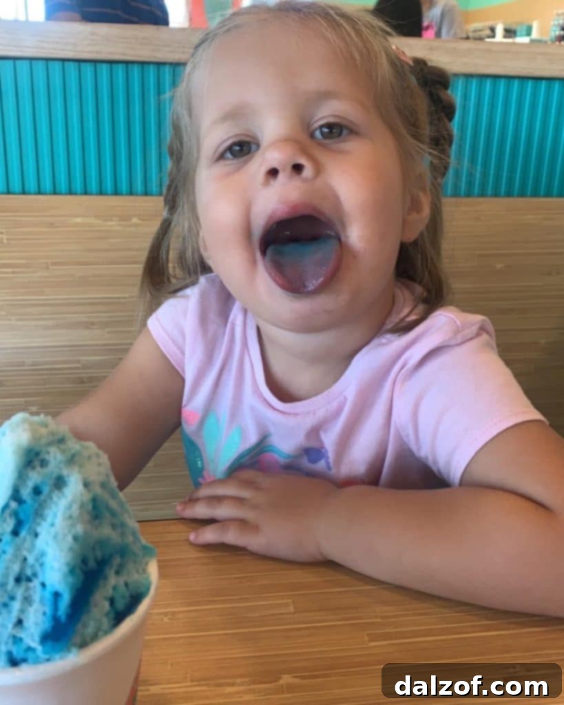 A young child happily enjoying a blue sno-cone, reflecting the simple joys of childhood treats