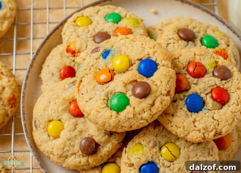 A tray of freshly baked peanut butter oatmeal M&M cookies cooling on a rack, some with additional M&M's pressed on top for visual appeal.