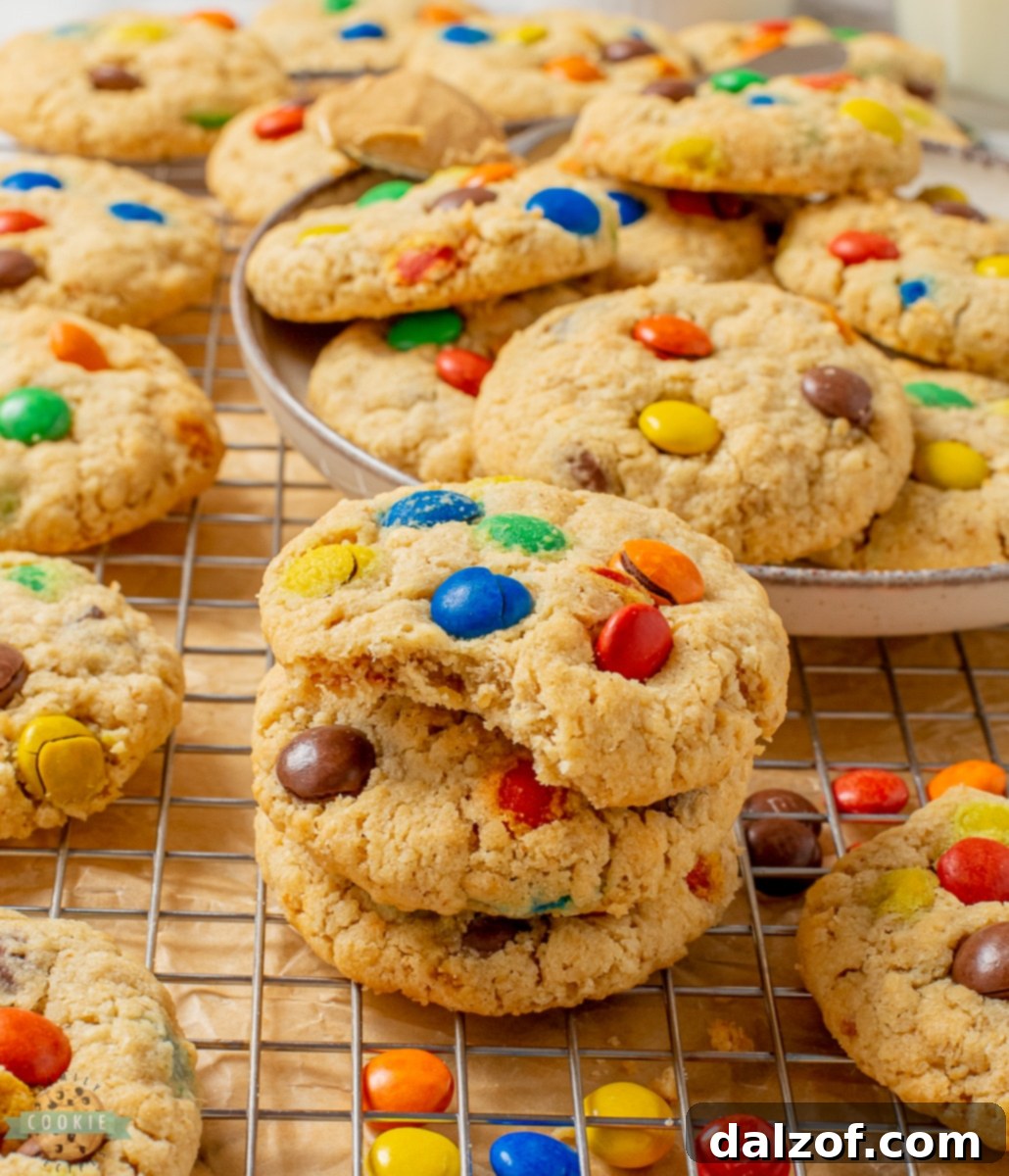 A close-up of a Peanut Butter Oatmeal M&M cookie with a bite taken out, showing its soft interior and melted M&M pieces.