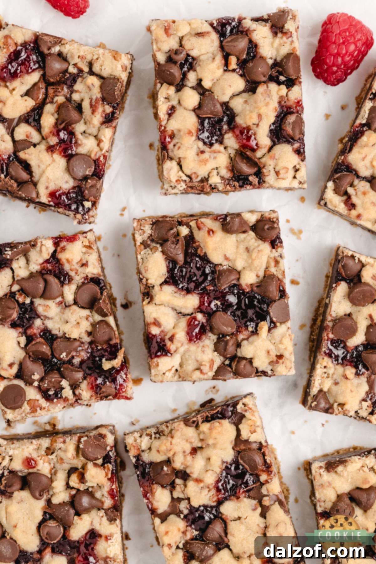 Squares of chocolate raspberry shortbread bars arranged on parchment paper.