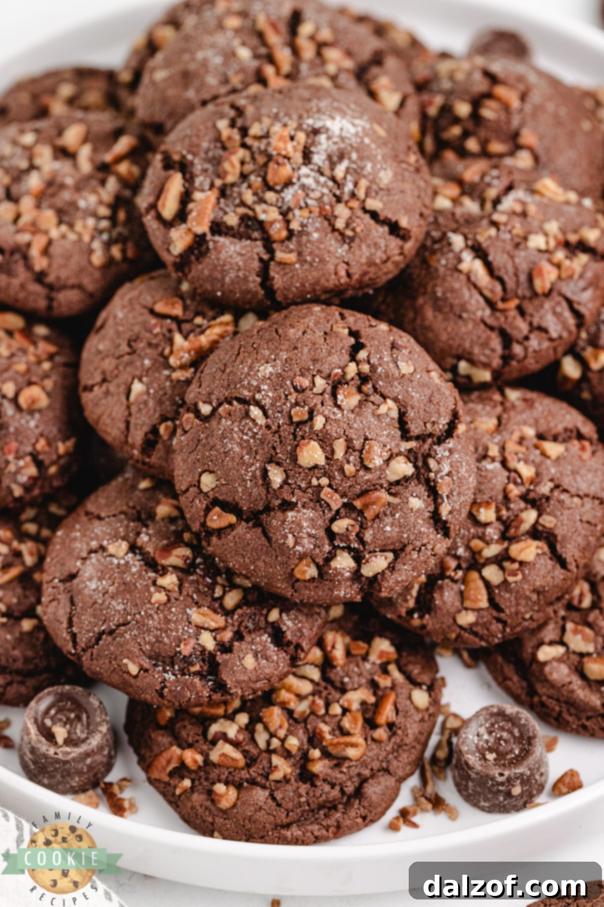 Decadent Chocolate Caramel Pecan Cookies 5 Chocolate caramel cookies with crispy pecan edges and soft chocolate centers displayed on a plate.