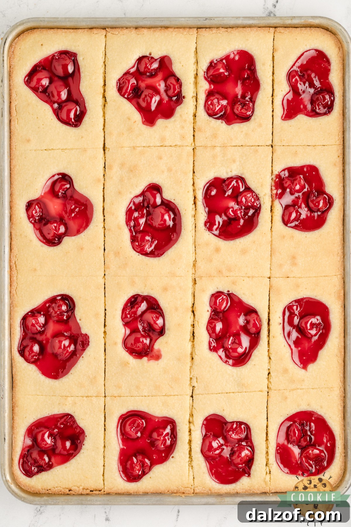 Overhead view of cherry pie cookie bars on a baking sheet cut into squares with cherry topping.