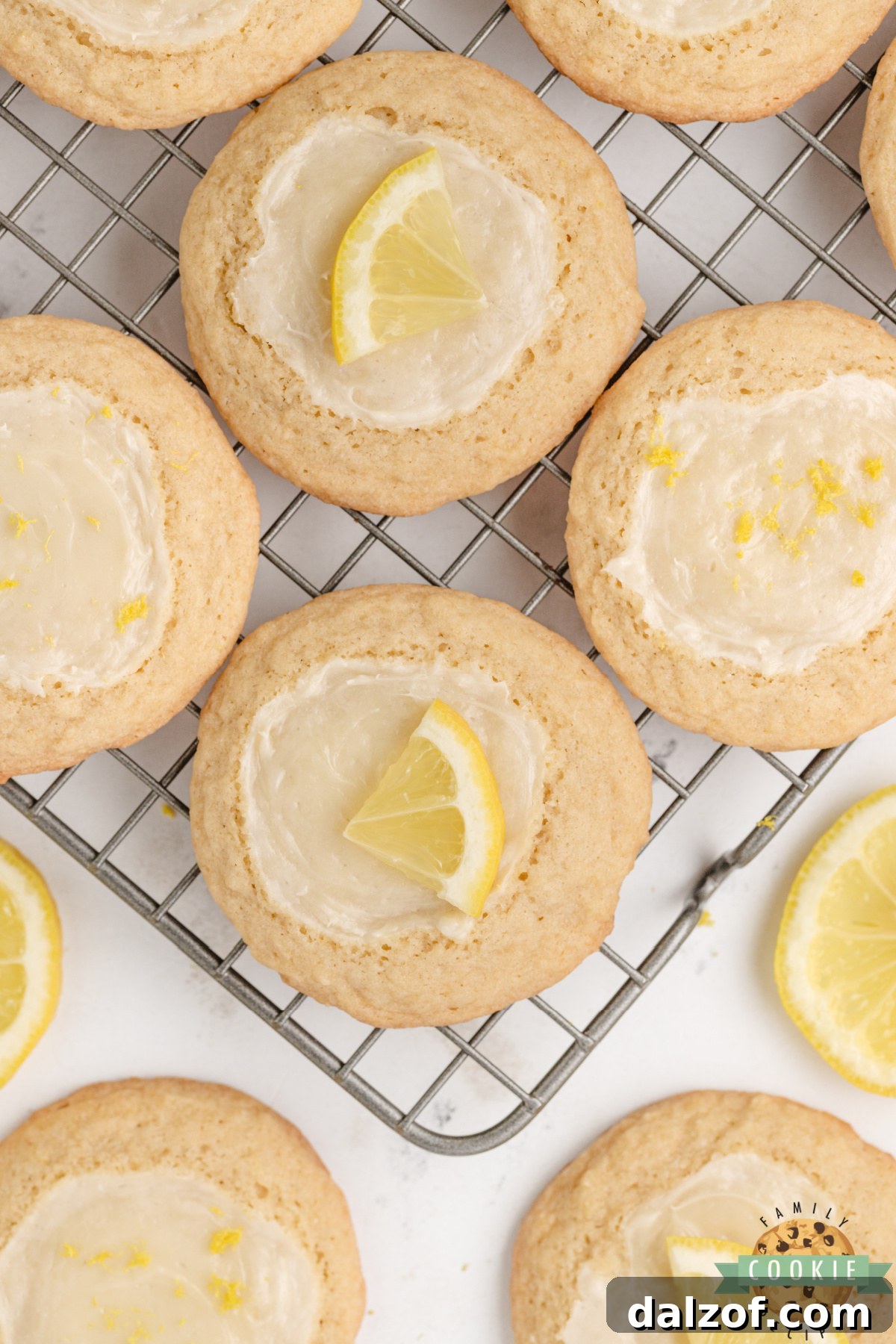 Lemon cheesecake cookies cooling on a wire rack with fresh lemons.