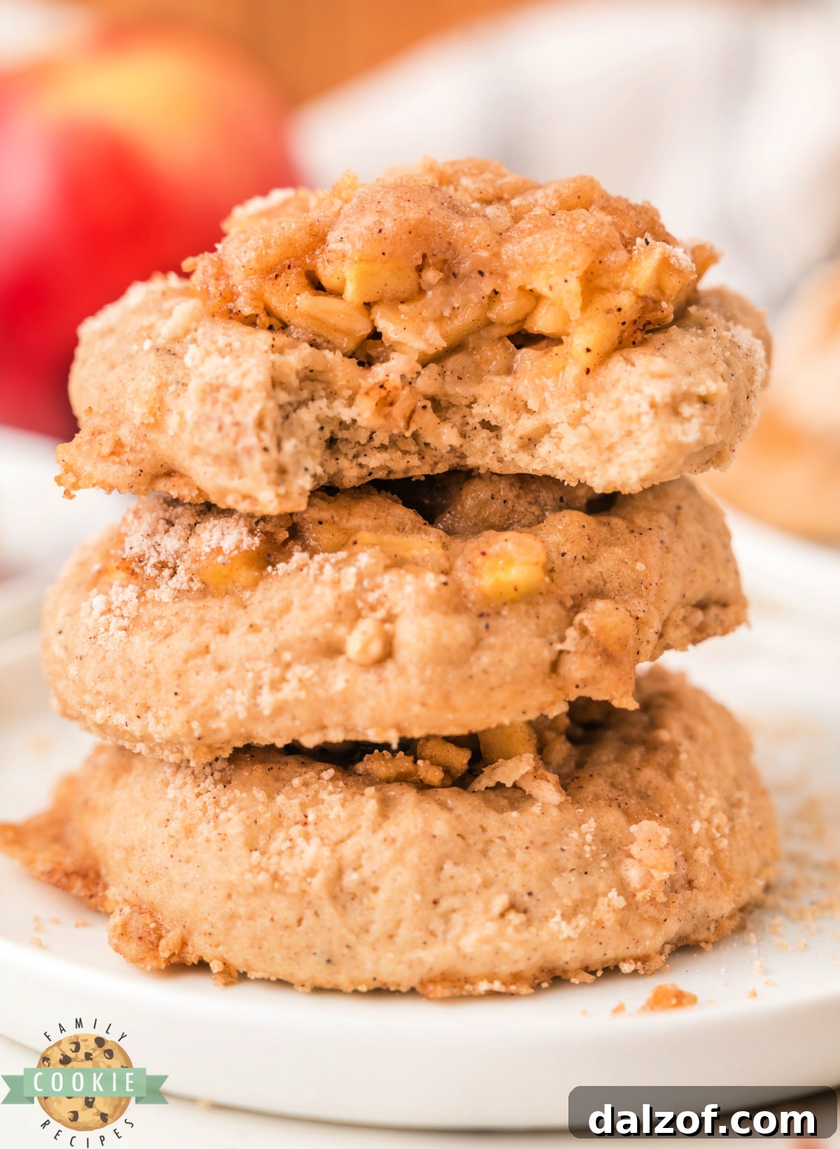 A plate of apple crisp cookies with icing drizzled on top showing the soft cookie base and apple crisp topping