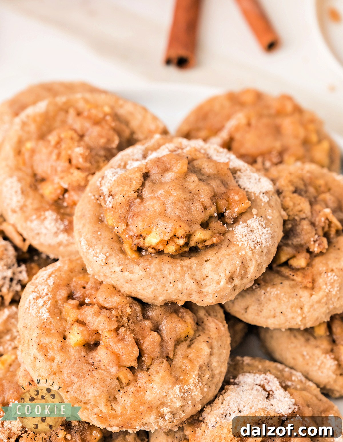 A plate of apple crisp cookies with icing drizzled on top showing the soft cookie base and apple crisp topping.