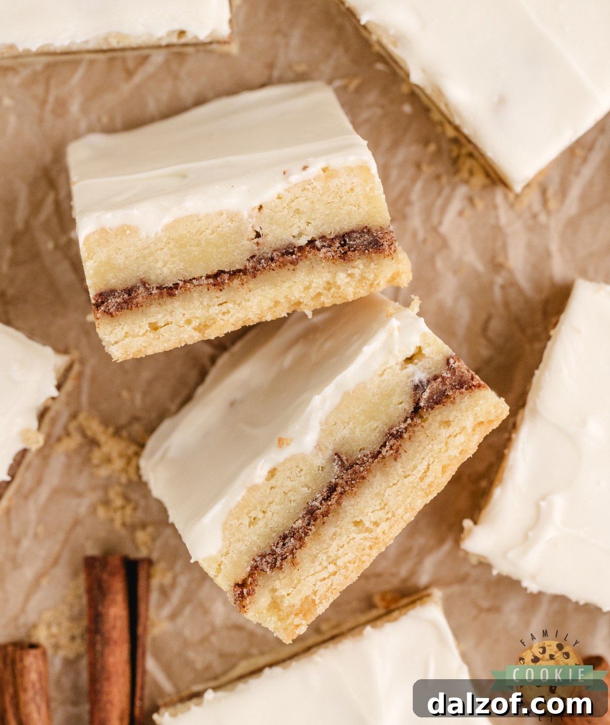 Cinnamon roll sugar cookie bars cut into squares showing the brown sugar cinnamon layer and cream cheese frosting on top.