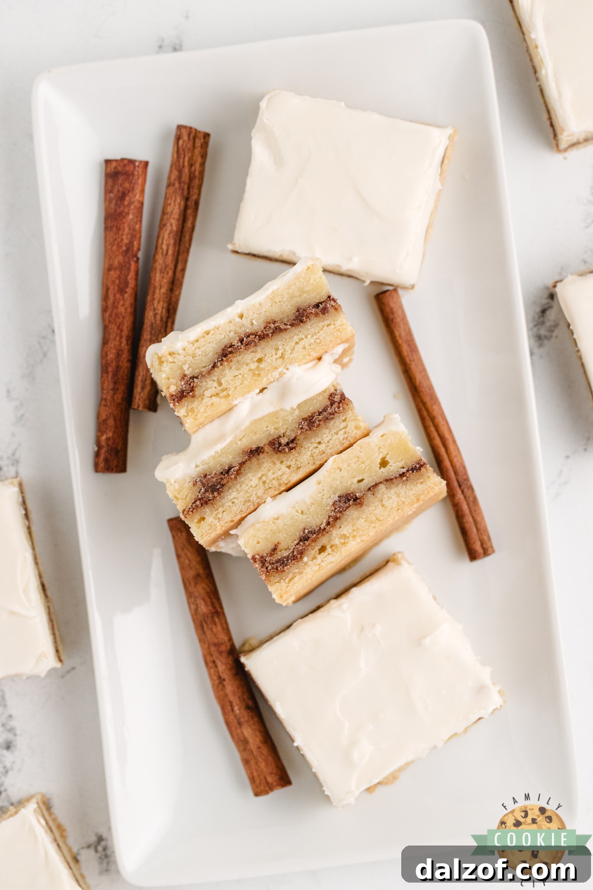 Cinnamon roll sugar cookie bars cut into squares showing the brown sugar cinnamon layer and cream cheese frosting on top.